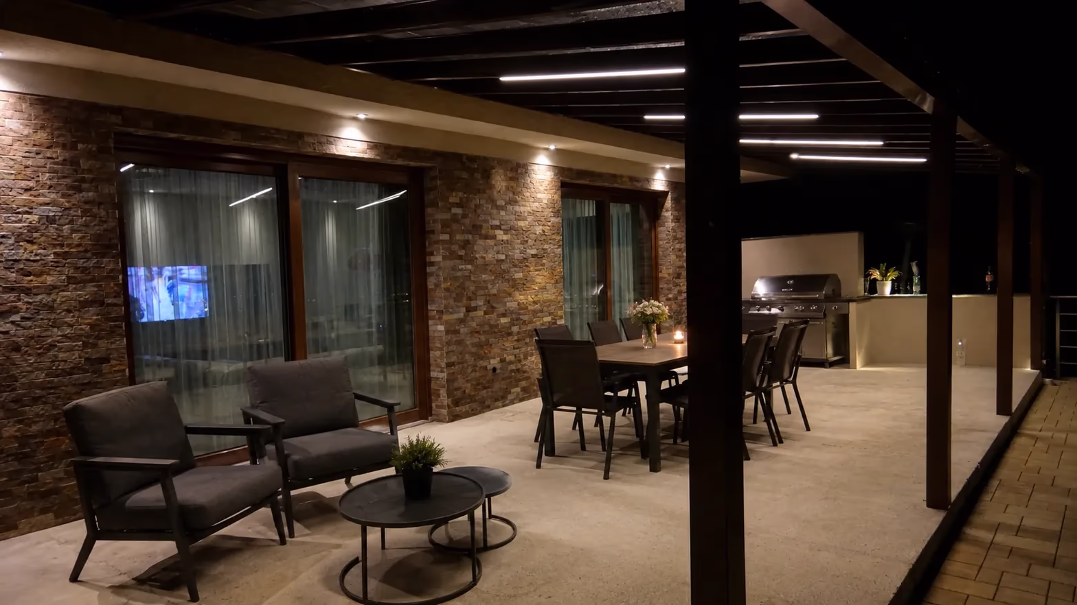 Wooden pergola with integrated LED strip lighting over a night-time terrace with a dining table