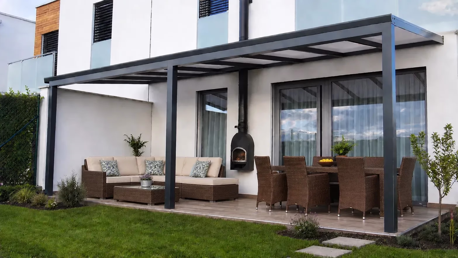 Anthracite Basic Class aluminium pergola over a terrace with a dining table and outdoor oven