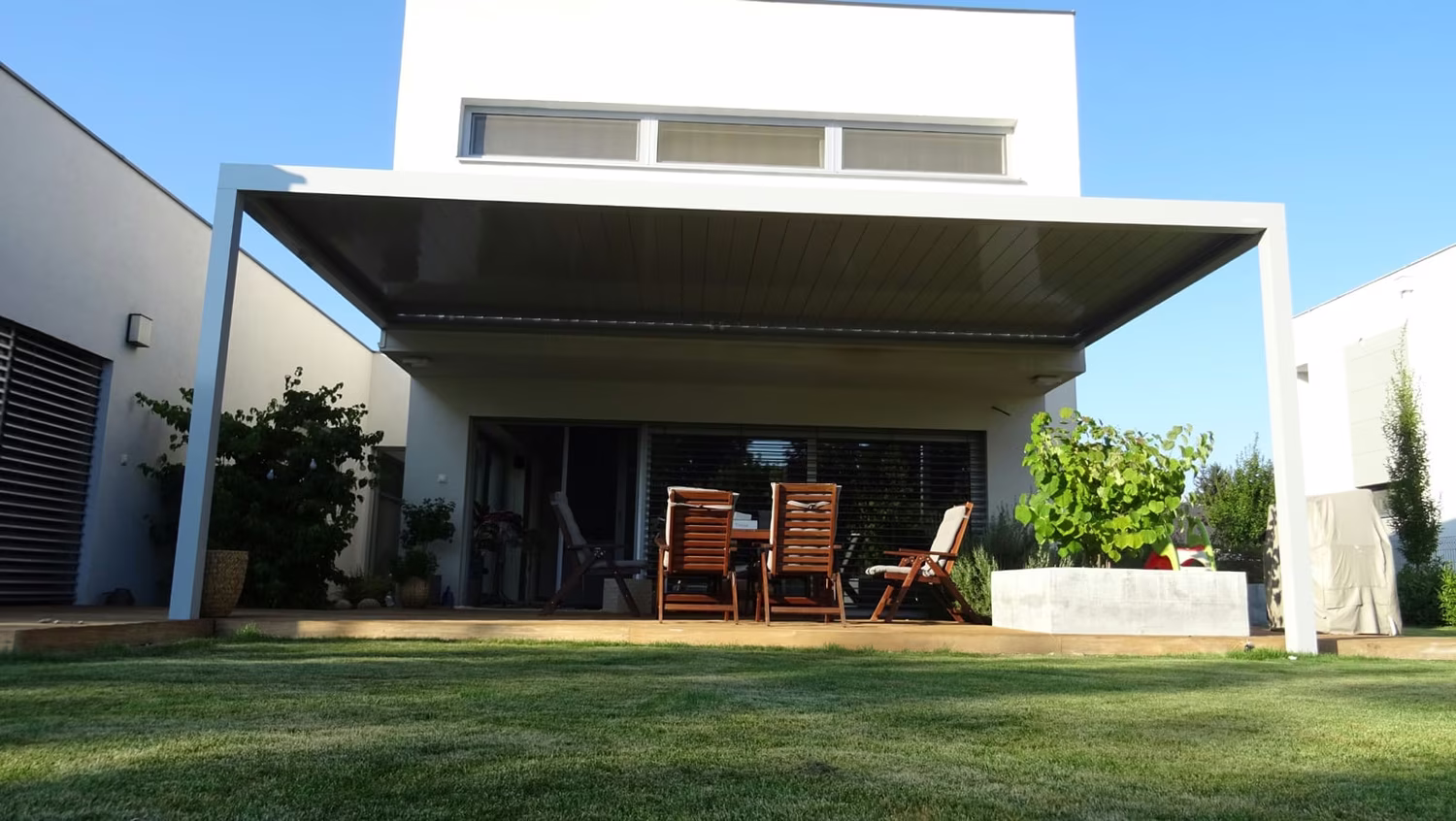 Bioclimatic aluminium pergola over a terrace with seating by a modern white house