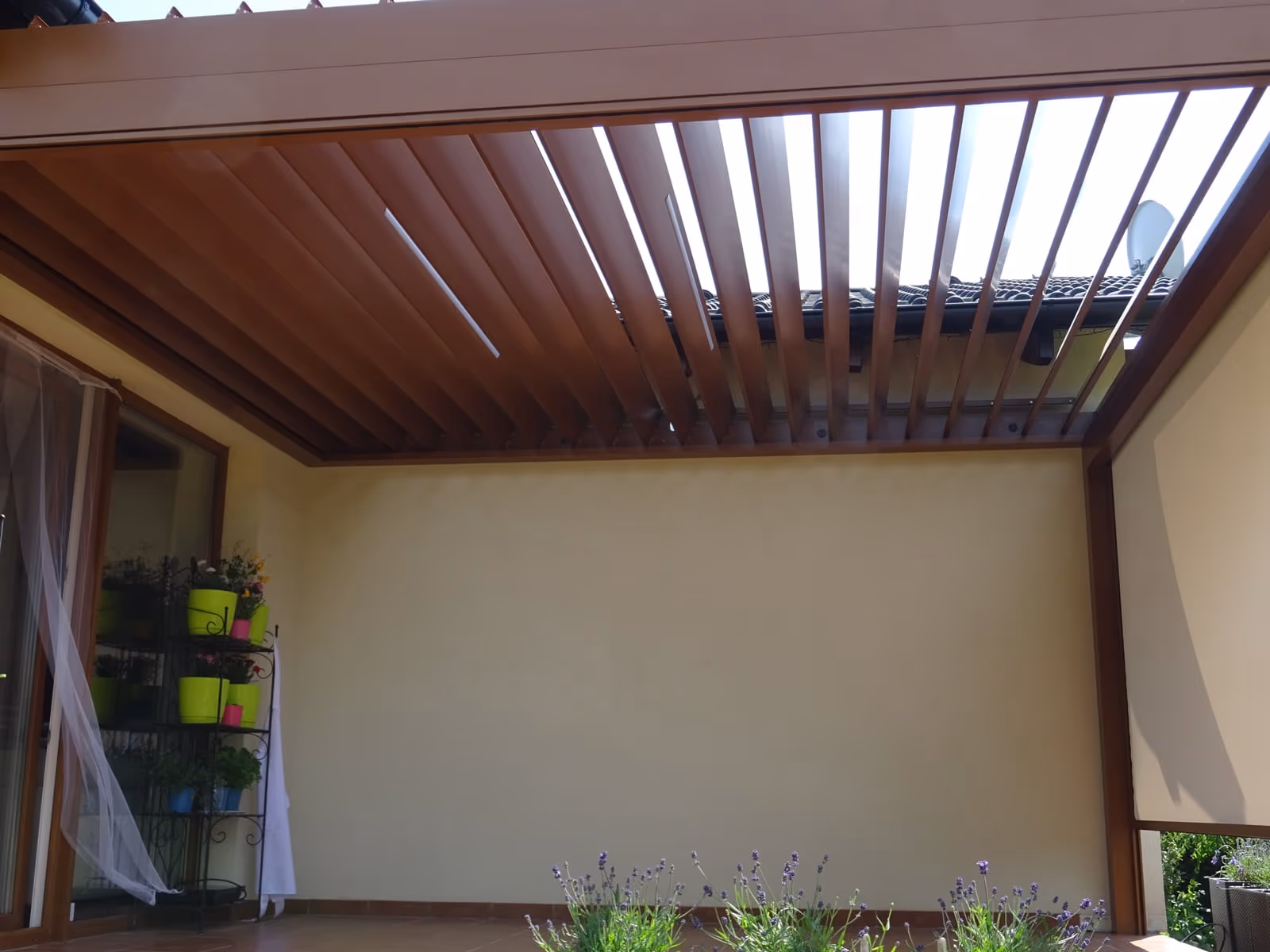Bioclimatic aluminium pergola with rotating louvres beside a modern new build
