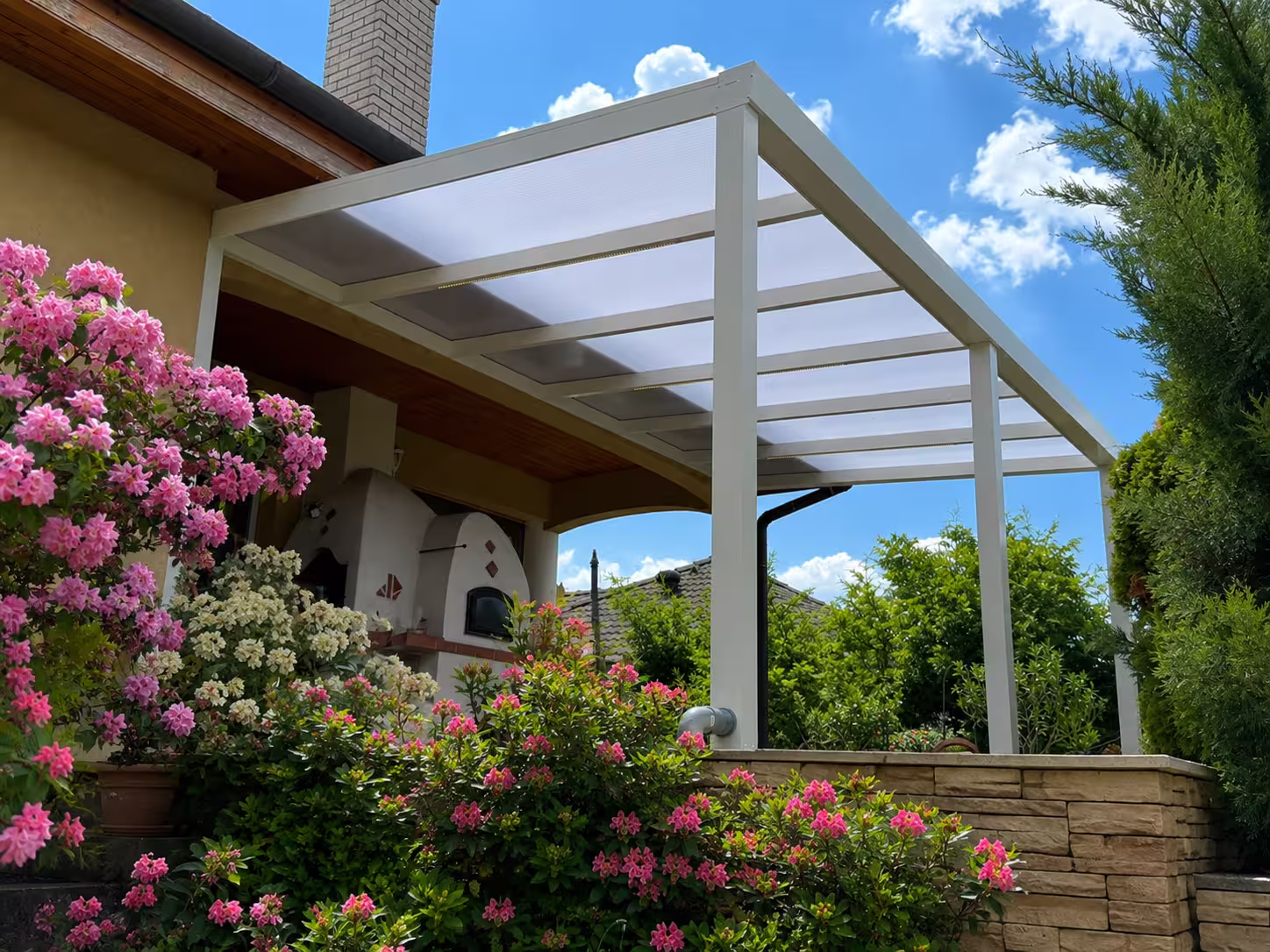 White Economic Class aluminium pergola in a flowering garden