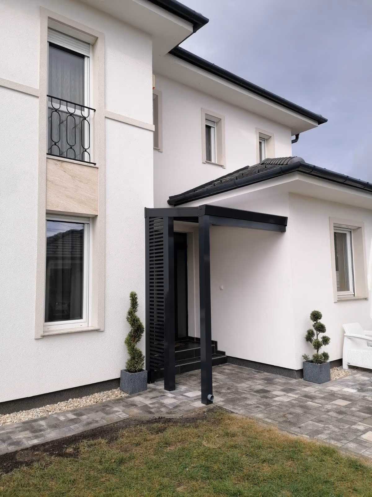 Economic Class aluminium pergola beside a modern grey house with steps