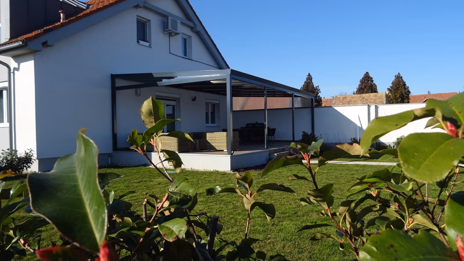 Economic Class aluminium pergola beside a house with a sloped roof and a large window