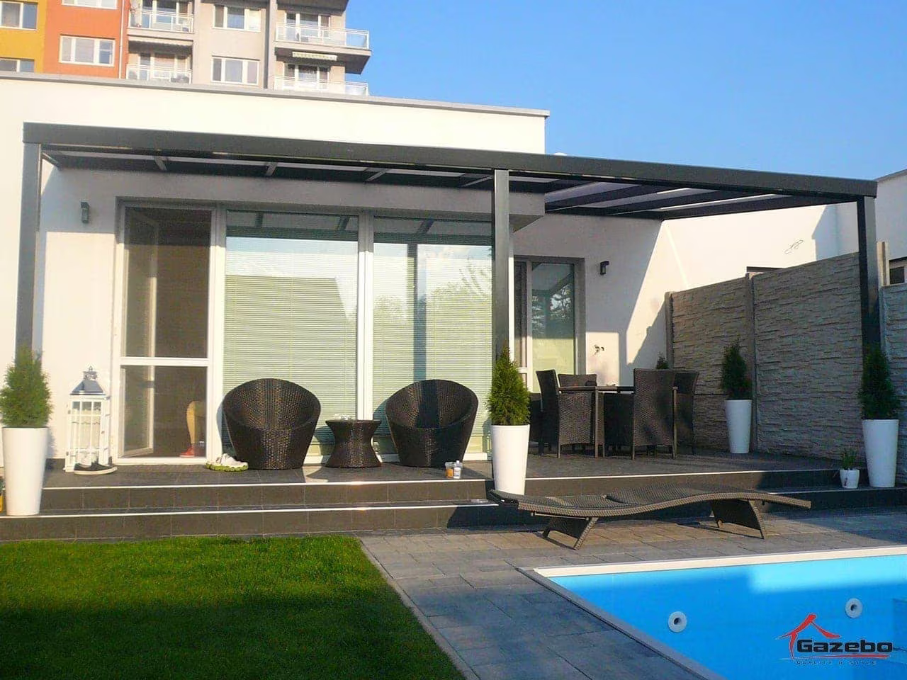 Anthracite Economic Class aluminium pergola over a terrace by a pool with rattan seating