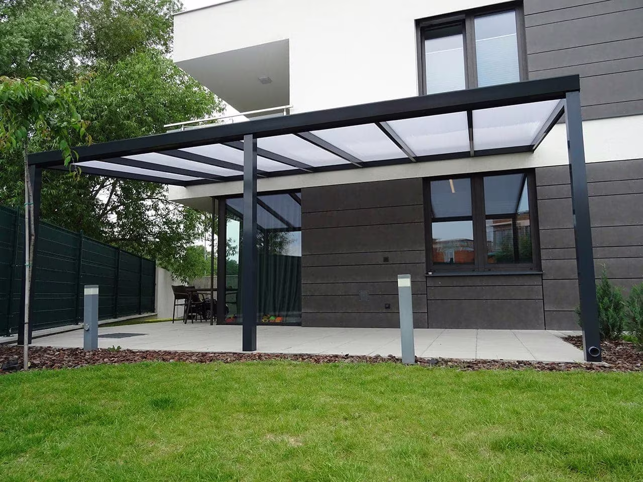 Anthracite Economic Class aluminium pergola beside a modern house with a lawn