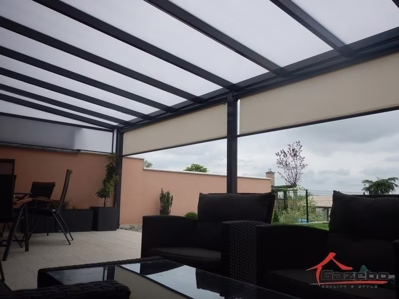 Anthracite Economic Class aluminium pergola over a terrace with a rattan lounge set