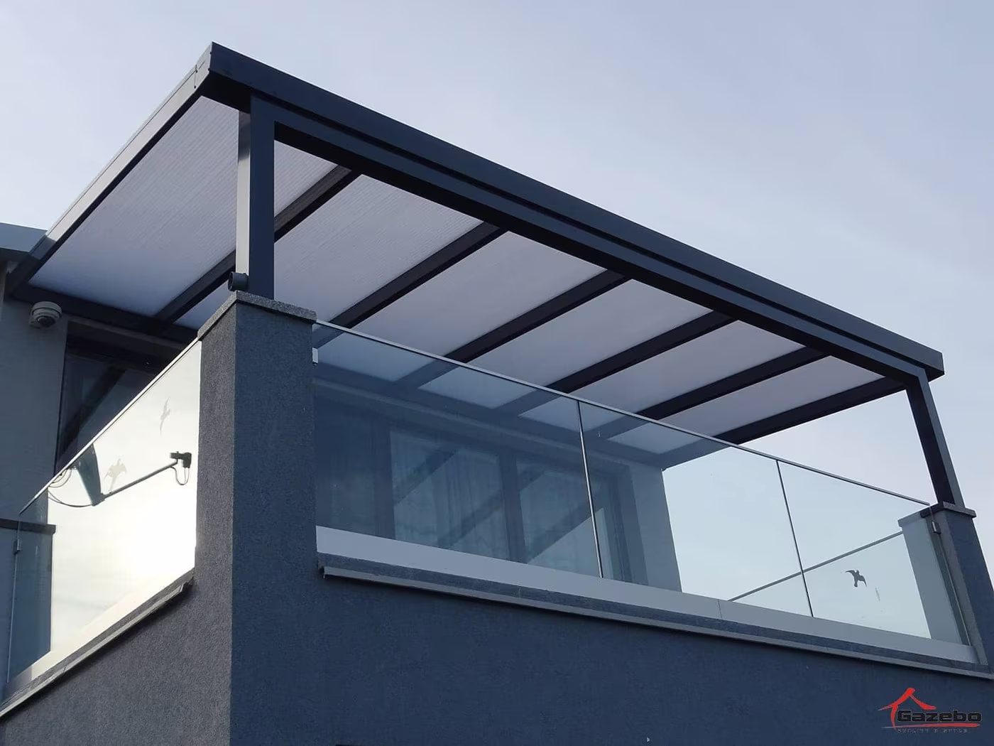 Close-up of an anthracite Economic Class aluminium pergola with a glass balustrade and polycarbonate roof