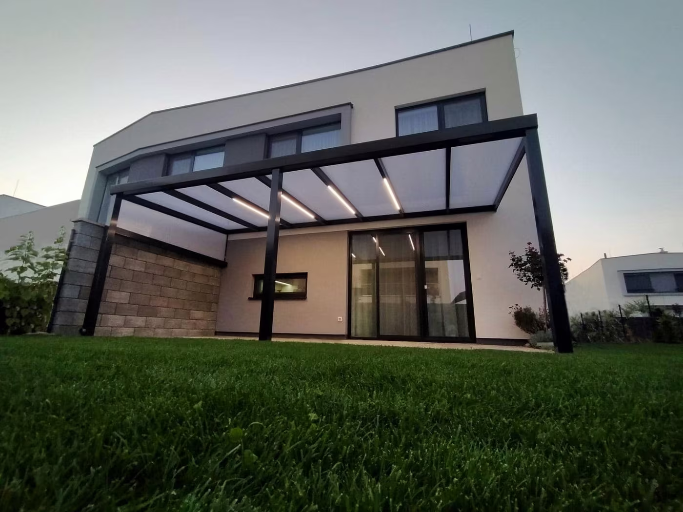 Anthracite Economic Class aluminium pergola beside a modern house at dusk