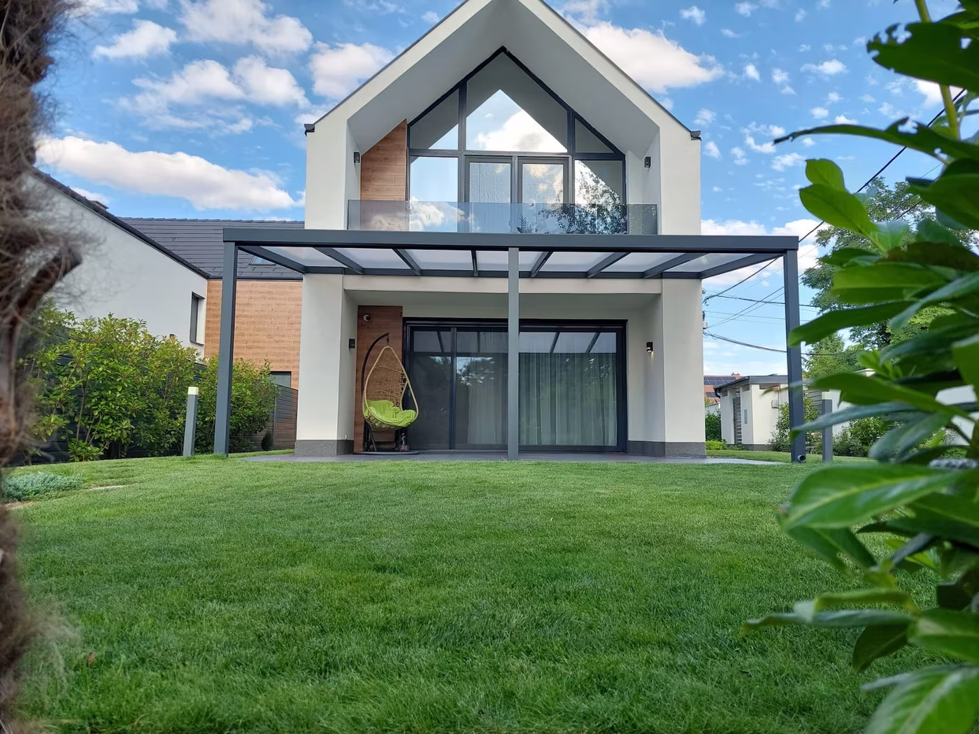 Anthracite Economic Class aluminium pergola over the terrace of a modern gable-roofed house