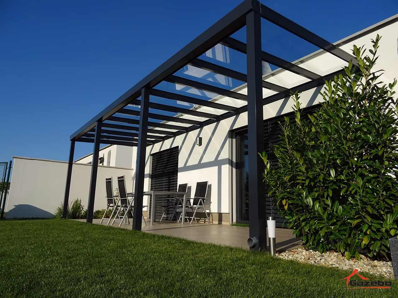 Top Class aluminium pergola with a dining set beside a white house