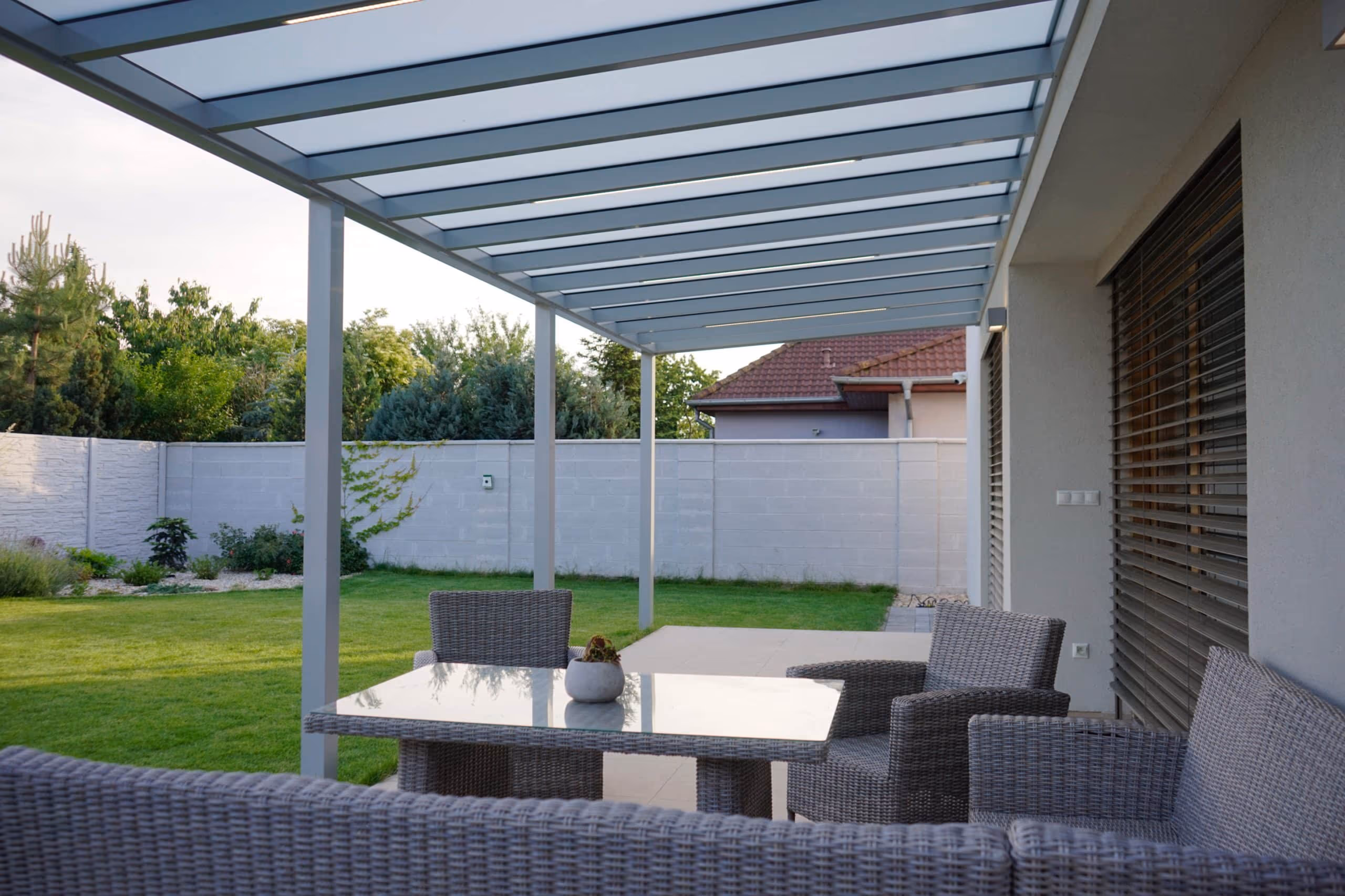 Top Class aluminium pergola beside a house with a wood facade