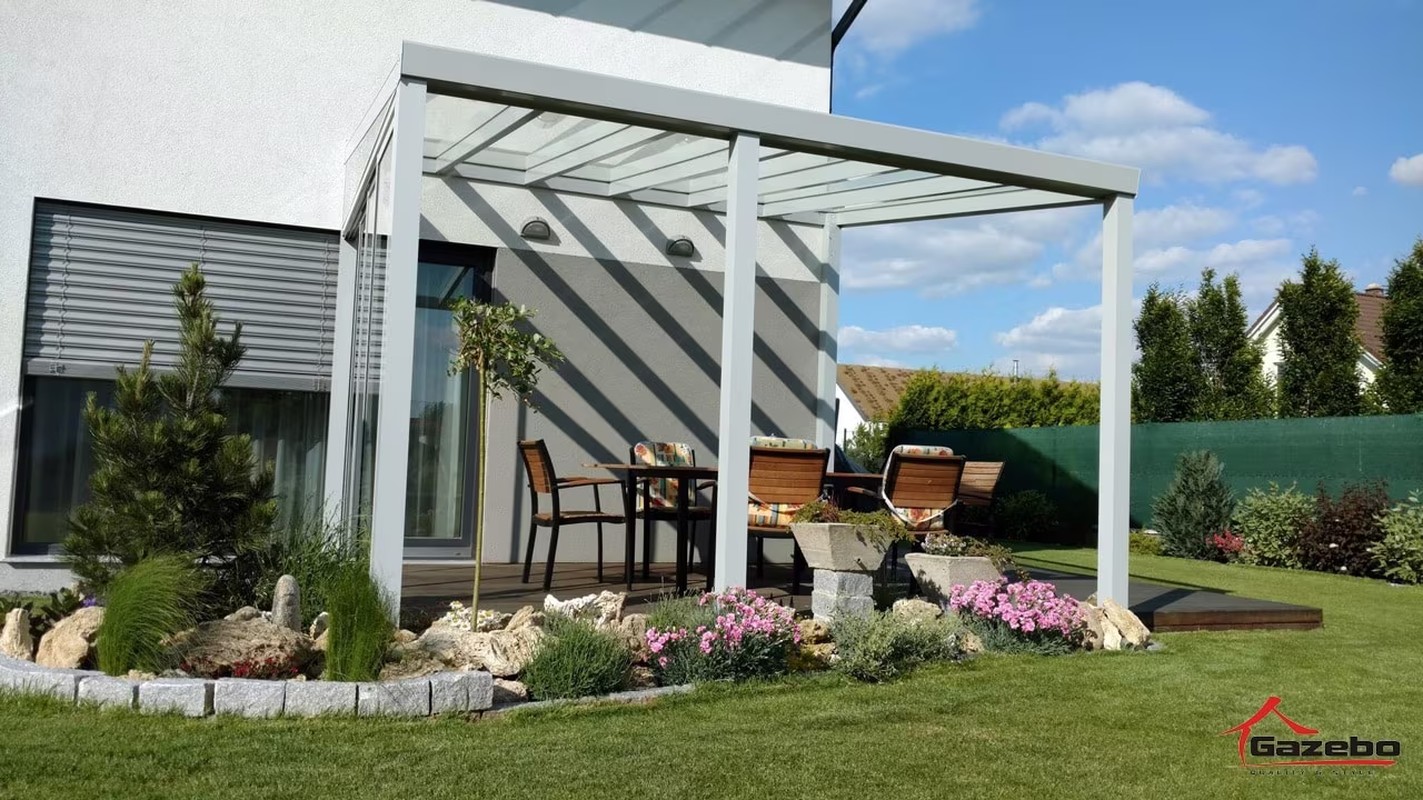 White Top Class aluminium pergola over a terrace with a dining set and a landscaped garden