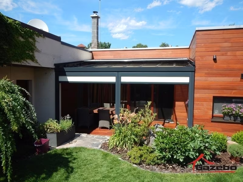 Anthracite Top Class aluminium pergola over a terrace with seating by a wood-clad house