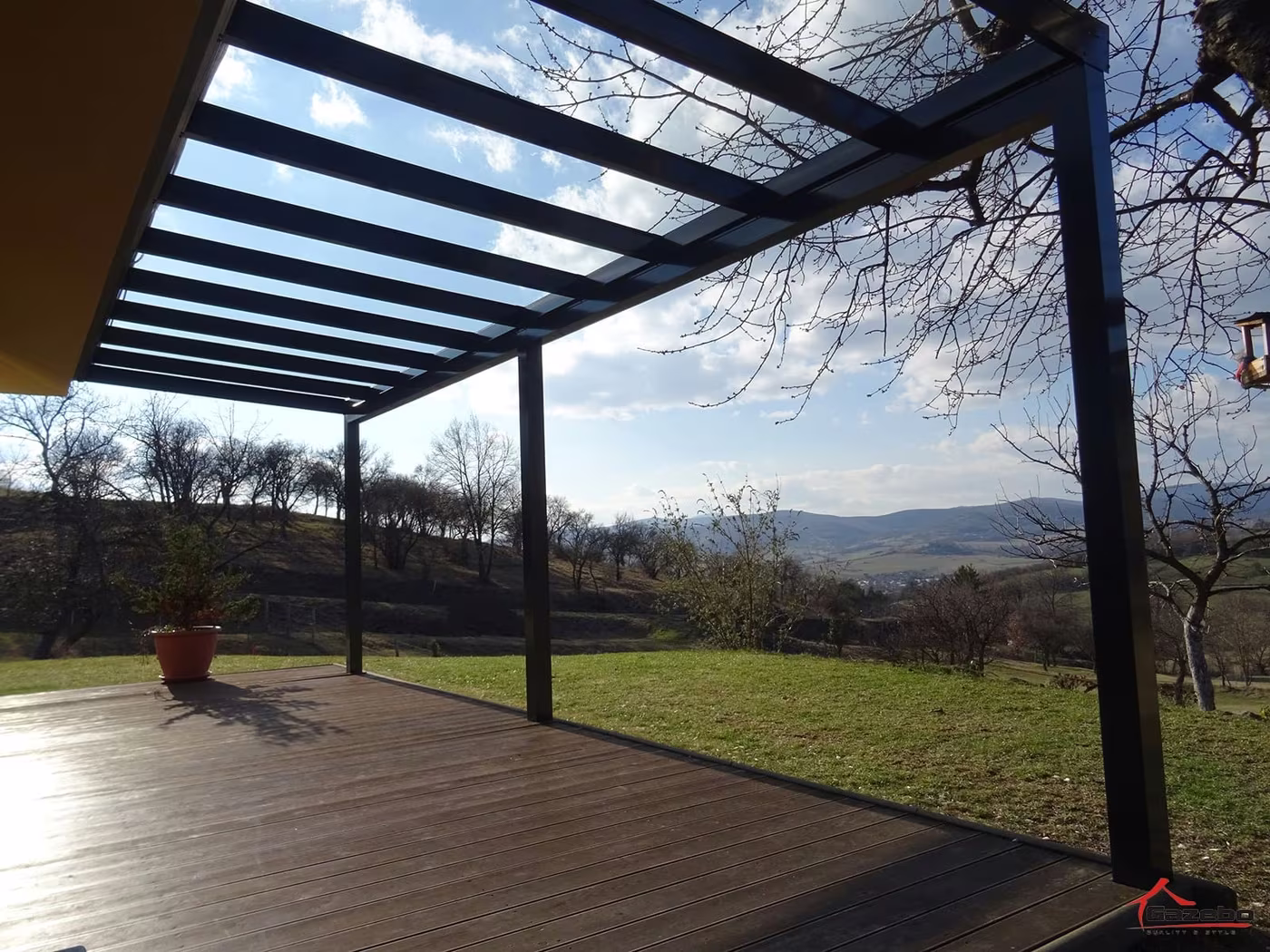 Anthracite Top Class aluminium pergola over a wood deck with a countryside view