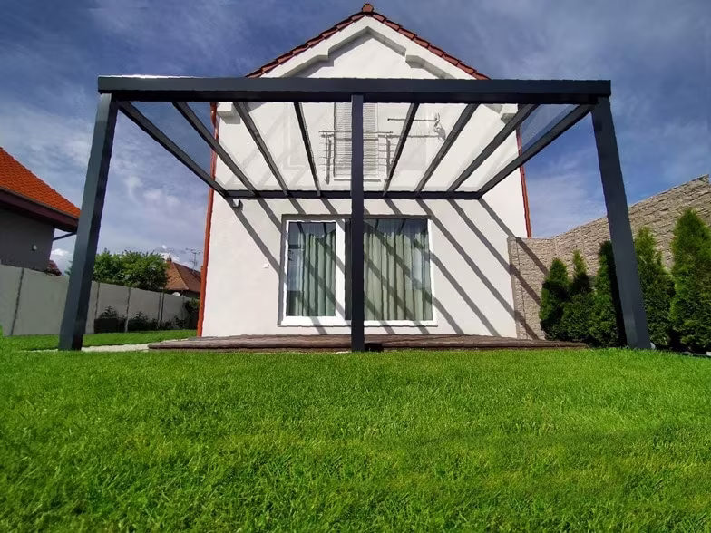 Anthracite Top Class aluminium pergola beside a white gable-roofed house with glazed doors