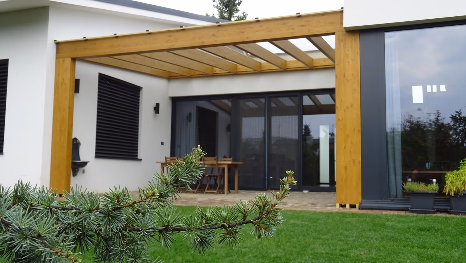 Milano wooden pergola in light-toned timber over a dining set