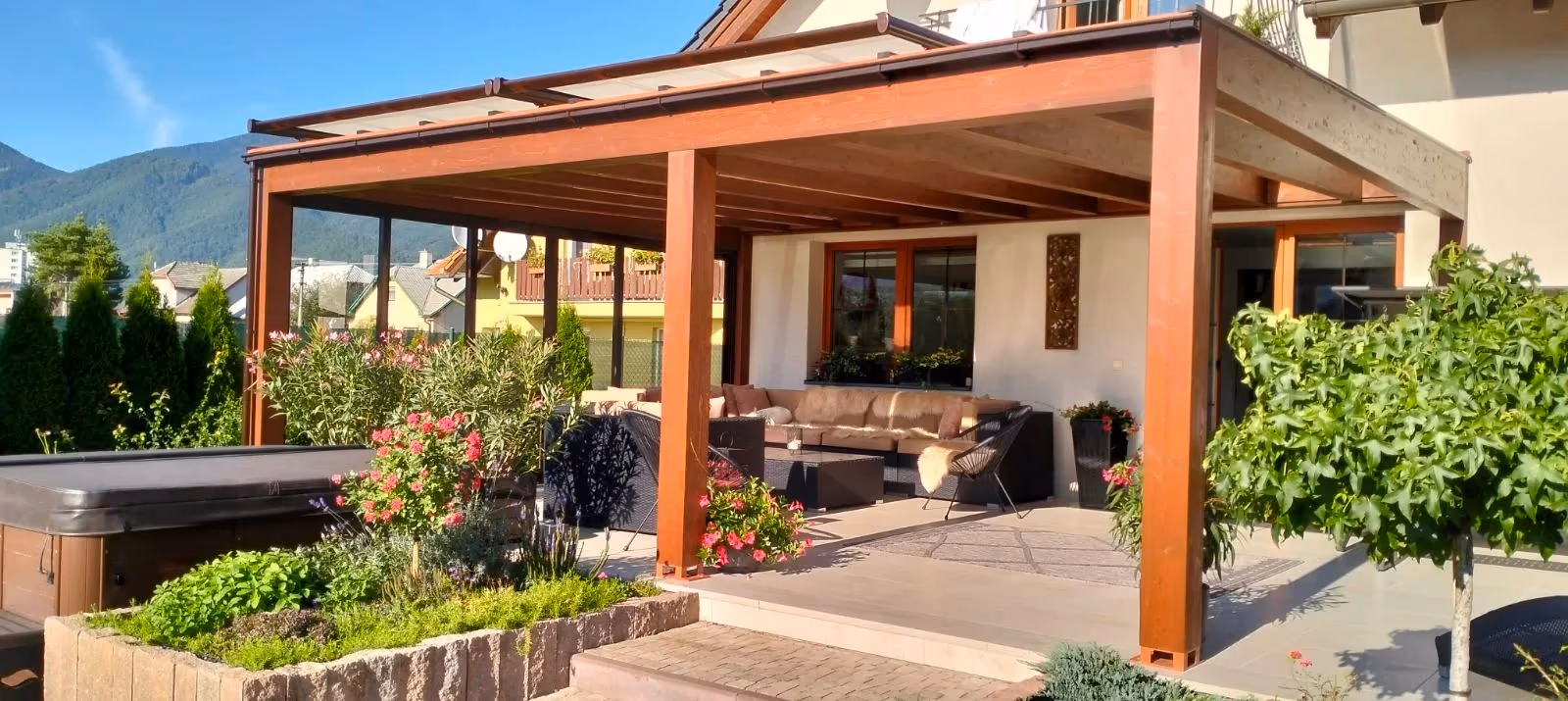 Milano wooden pergola with a sofa set beside a dark-coloured family home