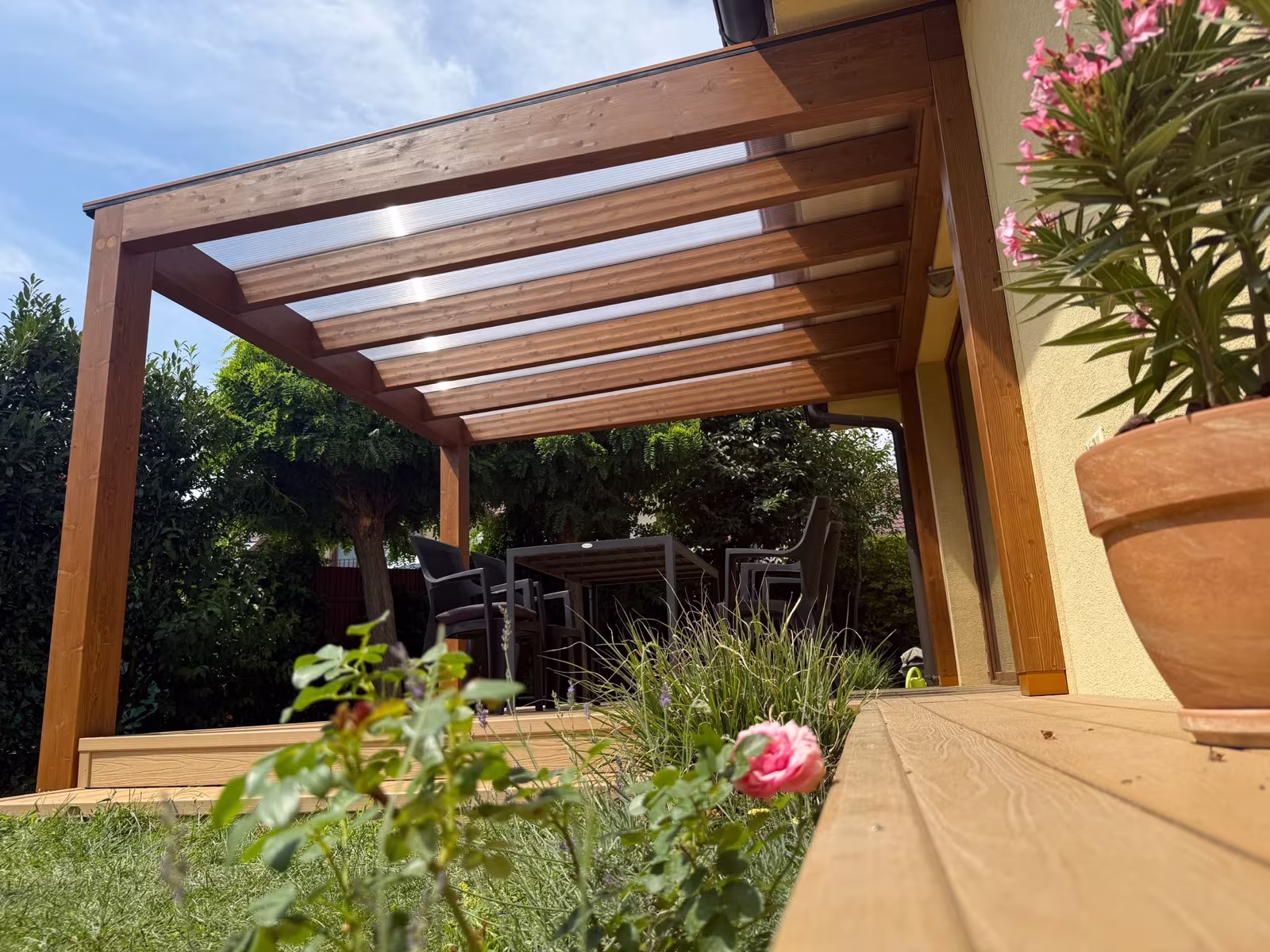 Milano wooden pergola with a transparent polycarbonate roof by a family house terrace