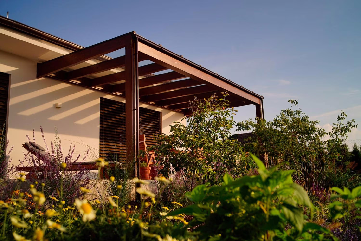 Milano wooden pergola with a slatted wooden side and a flower garden