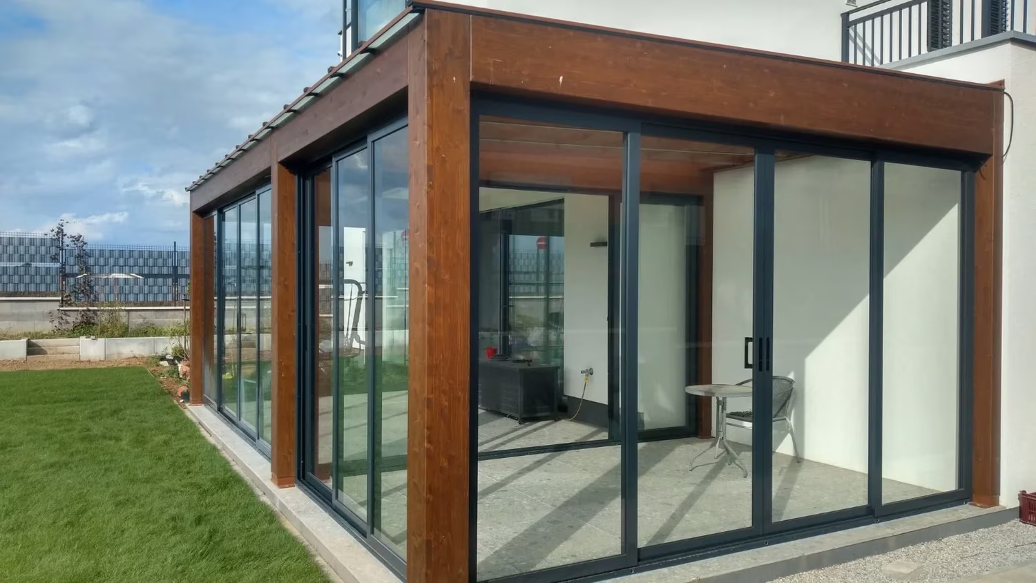 Glazed Milano wooden pergola as a living space by a house