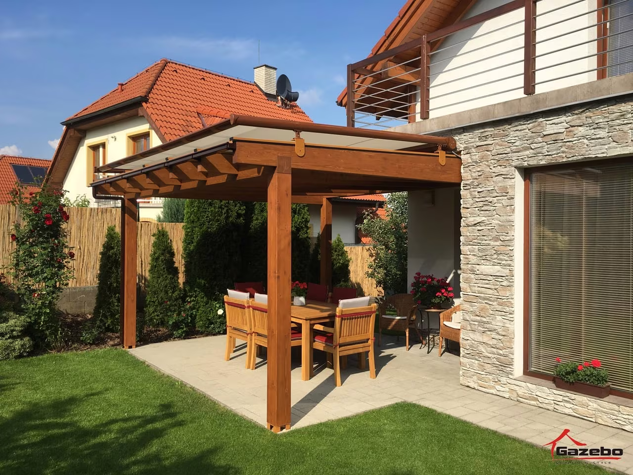 Fenix wooden pergola over a paved terrace with a dining set by a stone-clad house