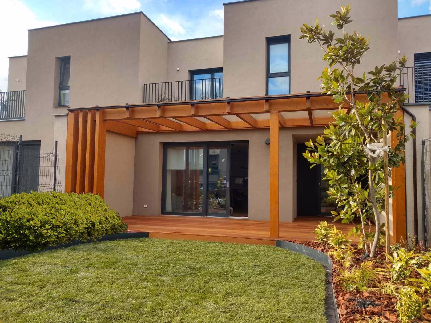 Fenix wooden pergola by a modern two-storey house over a wood deck